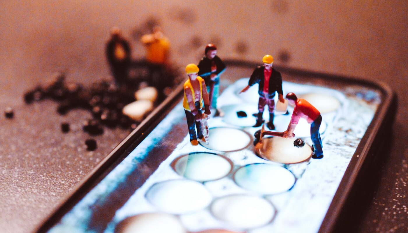tiny model construction workers, working on a mobile phone screen