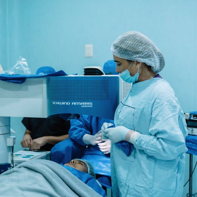 Medical professionals performing eye surgery in a sterile clinic environment.